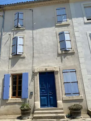 a building with a blue door and windows at Stylish large house with heated pool in historic village in Bize-Minervois