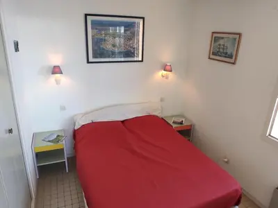 a red bed in a small room with two lamps at T2 Spacieux, Proche Plage, Parking Privé - FR-1-796-82 in Gruissan