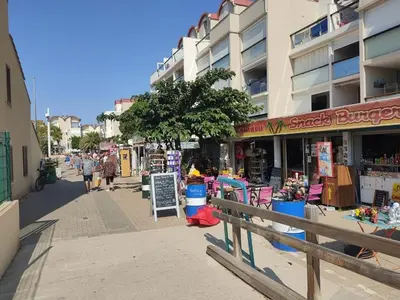 a city street with a store with people walking on the sidewalk at T2 Spacieux, Proche Plage, Parking Privé - FR-1-796-82 in Gruissan