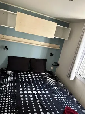 a bedroom with a black and white bed and a window at Mobil-home 3 ch camping TOHAPI in Port-la-Nouvelle