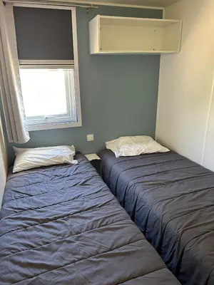 two beds in a small room with a window at Mobil-home 3 ch camping TOHAPI in Port-la-Nouvelle