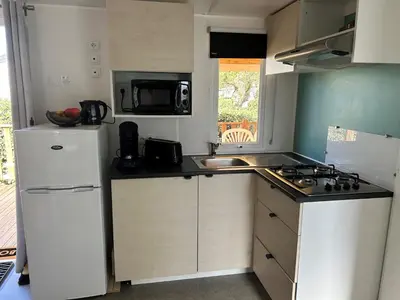a small kitchen with a white refrigerator and a sink at Mobil-home 3 ch camping TOHAPI in Port-la-Nouvelle