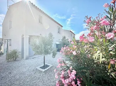 a white building with flowers in front of it at Villa avec piscine privée in Sallèles-dʼAude