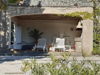 a patio with three white chairs and a table at Alzina in Vingrau