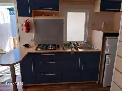 a small kitchen with blue cabinets and a sink at Mobil-home Port la Nouvelle in Port-la-Nouvelle