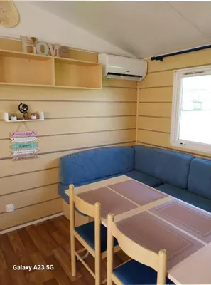 a living room with a blue couch and a table at Mobil-home Port la Nouvelle in Port-la-Nouvelle