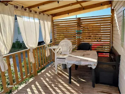 a patio with a table and chairs on a deck at Mobil-home Port la Nouvelle in Port-la-Nouvelle