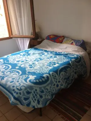 a bed with a blue and white blanket on it at Maison de Vacances in Pradelles-Cabardès