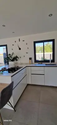 a kitchen with white cabinets and a stove top oven at Villa moderne avec piscine privée in Roubia
