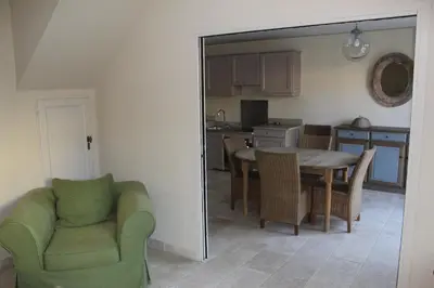 a kitchen and dining room with a table and a green chair at Maison 4 ou 6 personnes au cœur Corbières in Saint-Laurent-de-la-Cabrerisse