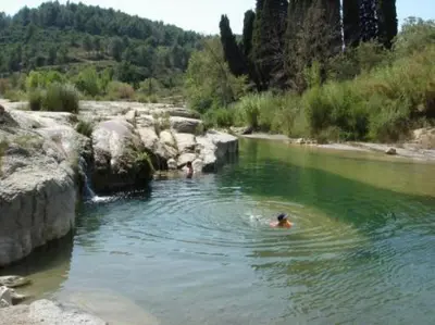 a person swimming in a river near some rocks at Maison 4 ou 6 personnes au cœur Corbières in Saint-Laurent-de-la-Cabrerisse