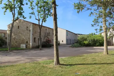 an old stone building with trees in front of it at Maison 4 ou 6 personnes au cœur Corbières in Saint-Laurent-de-la-Cabrerisse