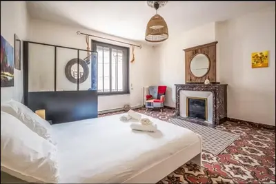 a bedroom with a large white bed and a fireplace at Comme une évidence in Carcassonne