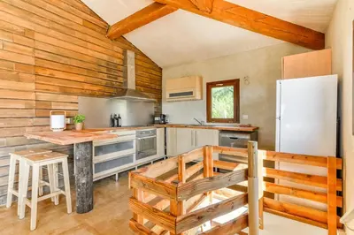 a kitchen with a white refrigerator and wooden walls at Gite la Bonté, chaleureux avec une vue enchantée in Vélieux