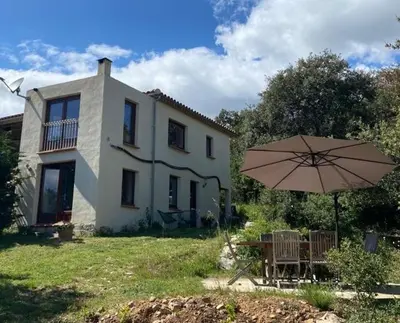 a table and an umbrella in front of a house at Gite la Bonté, chaleureux avec une vue enchantée in Vélieux