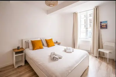 a bedroom with a large white bed with yellow pillows at Au Pied des Remparts-Cité Médiévale in Carcassonne