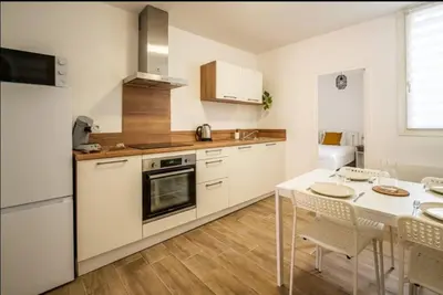 a white kitchen with a table and a dining room at Au Pied des Remparts-Cité Médiévale in Carcassonne