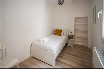 a small bedroom with a white bed with a yellow pillow at Au Pied des Remparts-Cité Médiévale in Carcassonne
