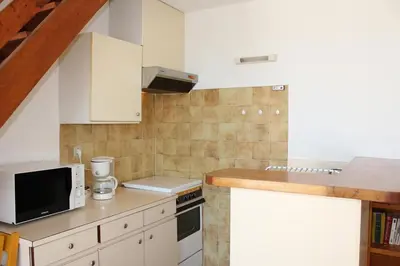 a small kitchen with white cabinets and a microwave at Appartement avec grande terrasse vue panoramique GN400-024 in Gruissan