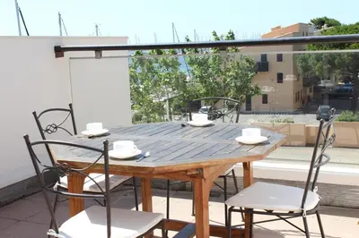 a wooden table and chairs on a balcony at Appartement avec grande terrasse vue panoramique GN400-024 in Gruissan