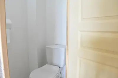 a white bathroom with a toilet and a door at Villa avec terrasse et garage proche plage GA120-038 in Gruissan