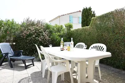 a white table with chairs and bottles of wine at Villa avec terrasse et garage proche plage GA120-038 in Gruissan