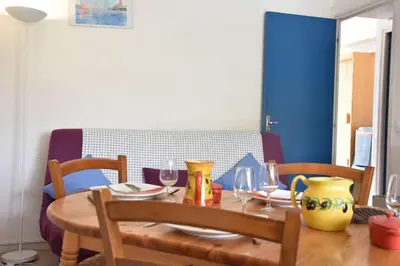 a dining room table with chairs and a table with wine glasses at Appartement 2 pièces - Gruissan GN580-028 in Gruissan
