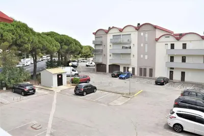a parking lot with cars parked in front of a building at Appartement 2 pièces - Gruissan GN580-028 in Gruissan