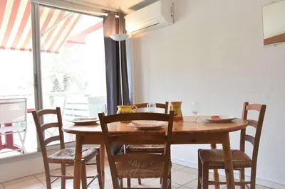 a wooden table and chairs in a room with a window at Appartement 2 pièces - Gruissan GN580-028 in Gruissan