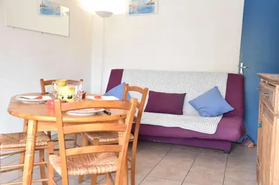 a dining room with a table and a couch at Appartement 2 pièces - Gruissan GN580-028 in Gruissan