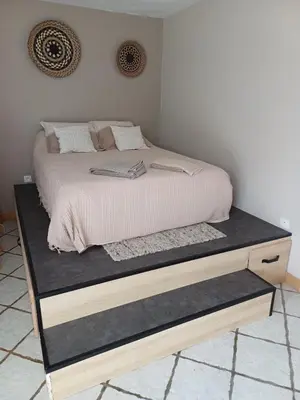 a bed with a wooden platform in a bedroom at Studio bord de mer in Port-la-Nouvelle