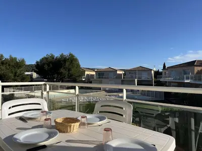 a white table and chairs on a balcony at Appartement climatisé avec piscine - Vue Clape GN190-711 in Gruissan