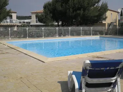 a swimming pool with two chairs next to it at Appartement climatisé avec piscine - Vue Clape GN190-711 in Gruissan