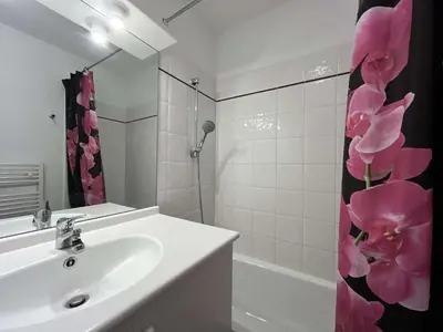 a bathroom with a sink and a shower curtain with pink flowers at Appartement climatisé avec piscine - Vue Clape GN190-711 in Gruissan
