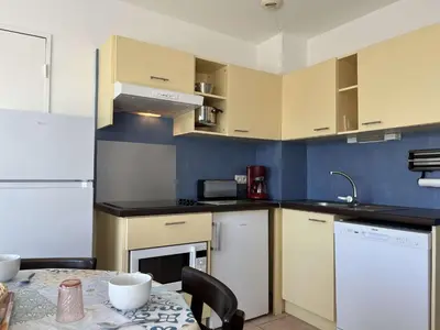 a kitchen with a table and a white refrigerator at Appartement climatisé avec piscine - Vue Clape GN190-711 in Gruissan