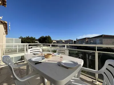 a white table and chairs on a balcony at Appartement climatisé avec piscine - Vue Clape GN190-711 in Gruissan