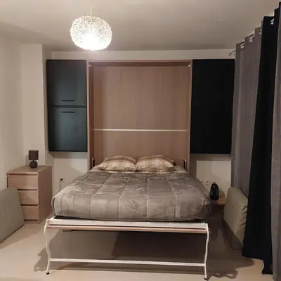 a bedroom with a large bed and a chandelier at Grand Studio à 300m de la plage dans Résidence calme - une seule pièce in Gruissan