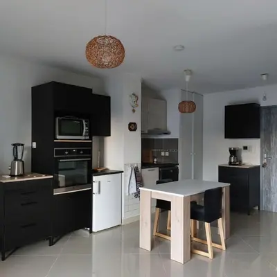 a kitchen with a white table and black cabinets at Grand Studio à 300m de la plage dans Résidence calme - une seule pièce in Gruissan
