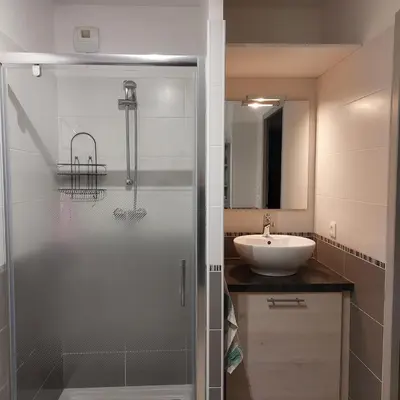 a bathroom with a glass shower and a sink at Grand Studio à 300m de la plage dans Résidence calme - une seule pièce in Gruissan