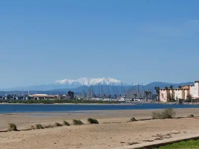 a beach with boats in the water and mountains at Grand Studio à 300m de la plage dans Résidence calme - une seule pièce in Gruissan