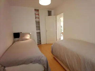 a bedroom with two beds and a door to a hallway at villa 2 chambres en rez-de-jardin in Puylaurens