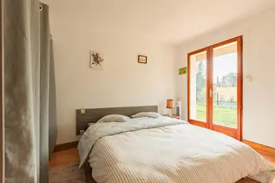 a white bedroom with a bed and a window at Le Coteau Ensoleillé - Climatisée avec piscine in Carcassonne