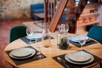 a wooden table with plates and wine glasses on it at Mezza'Cosy, apt avec parking à 2 pas de la Cité in Carcassonne