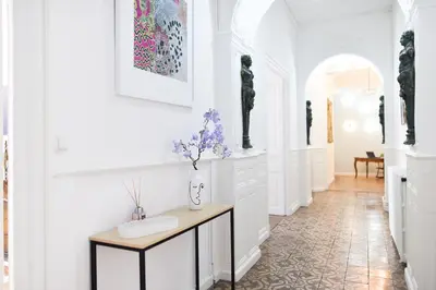 a hallway with white walls and a table with flowers on it at le RAMOND in Carcassonne