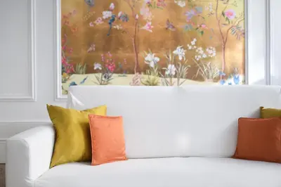 a white couch with colorful pillows in front of a painting at le RAMOND in Carcassonne
