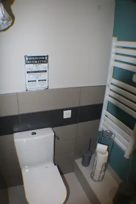 a bathroom with a toilet with a sign on the wall at L'Autan sage in Montgeard
