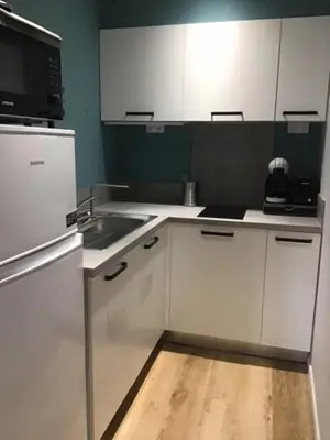 a kitchen with white cabinets and a wooden floor at L'Autan sage in Montgeard