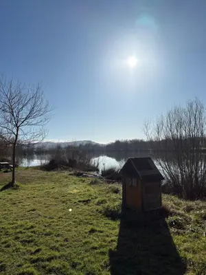 a dog house sitting in a field next to a body of water at Lac de Latournerie in Cazals-des-Baylès