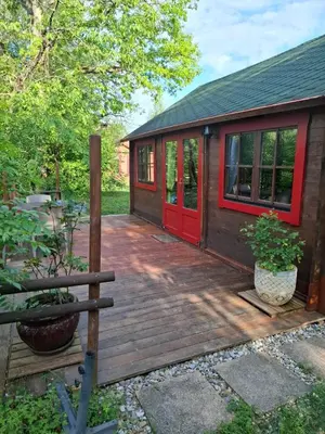 a cabin with a red door on a deck at Lac de Latournerie in Cazals-des-Baylès