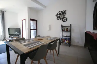 a dining room table with chairs and a clock on the wall at T3 de 70m2 avec sauna, piscine intérieure chauffée in Siran